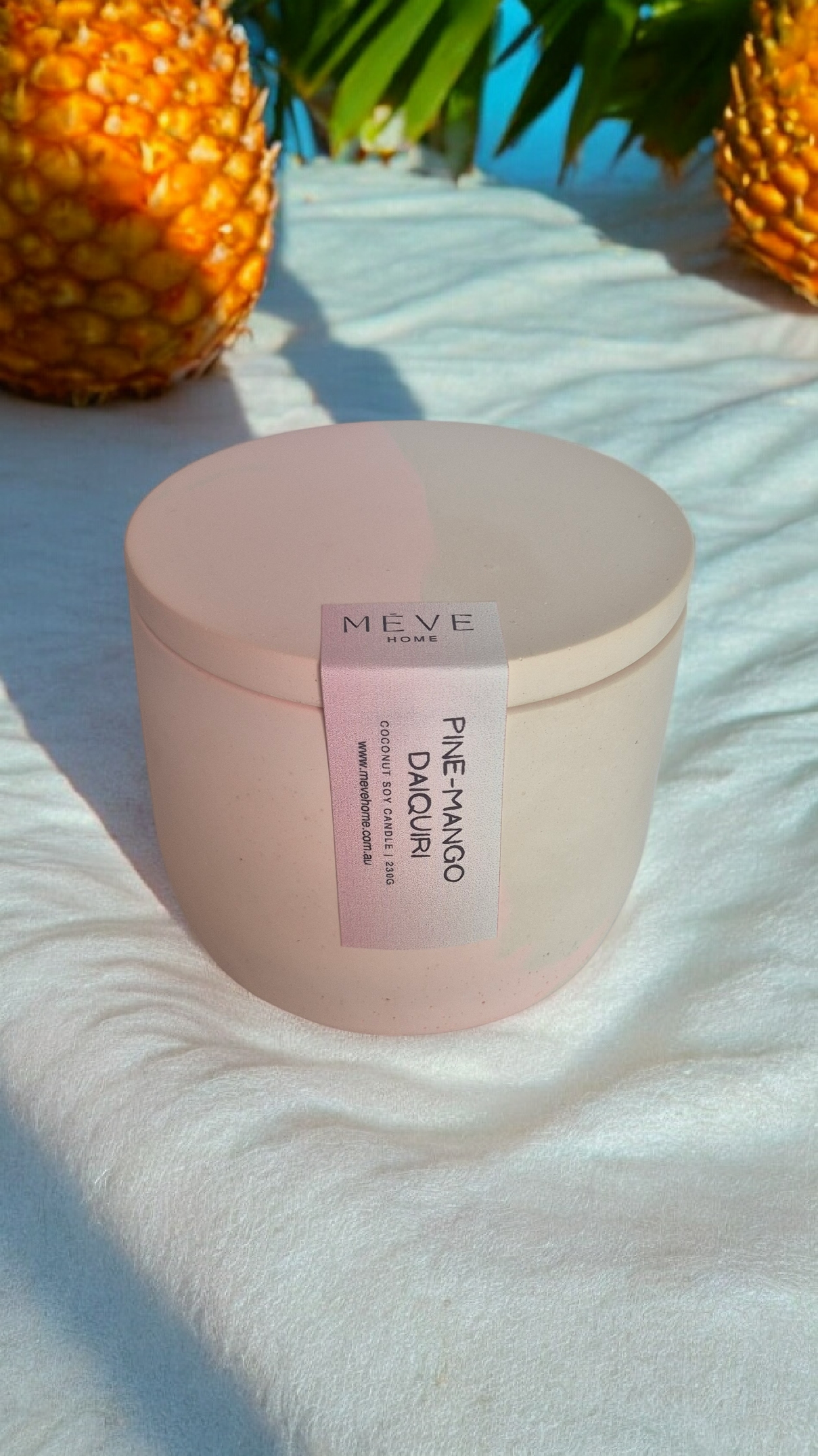 Pink container with a label on a white surface with pineapples in the background