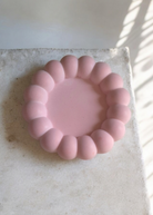 Pink silicone ring on a light stone surface with sunlight casting shadows.