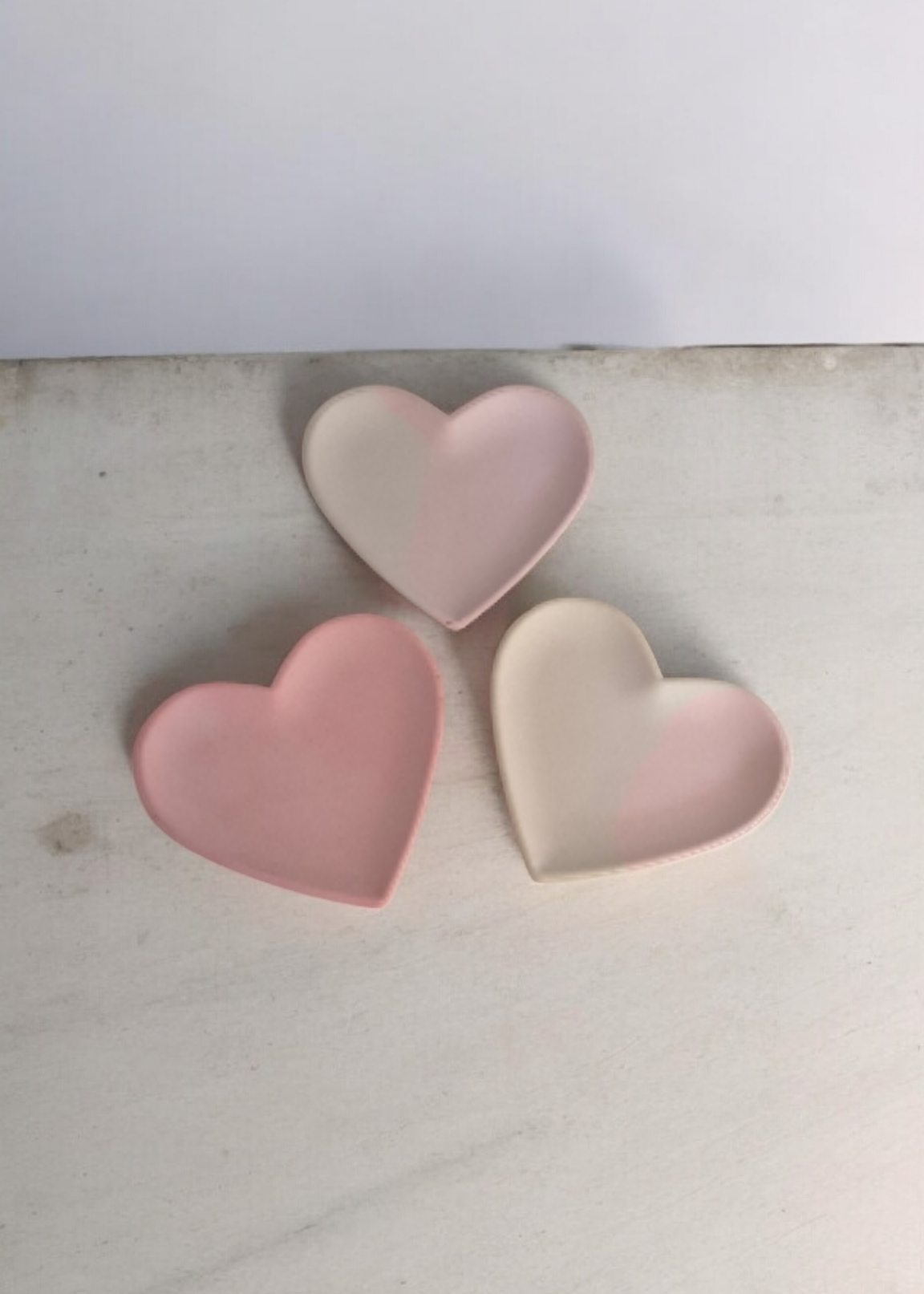 Two heart-shaped pink and beige objects on a light background